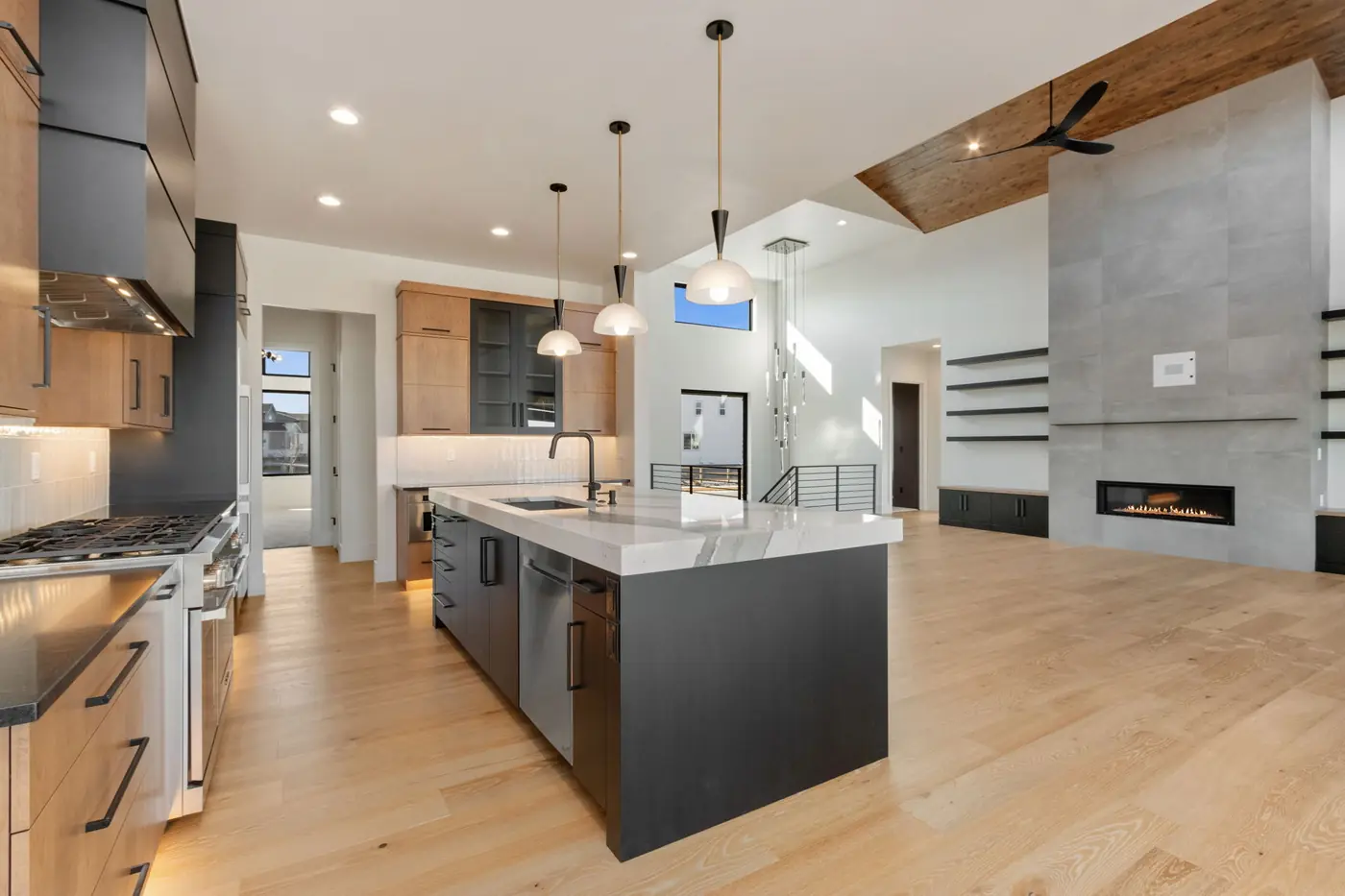 Open great room with vaulted wood ceiling, custom kitchen and modern fireplace